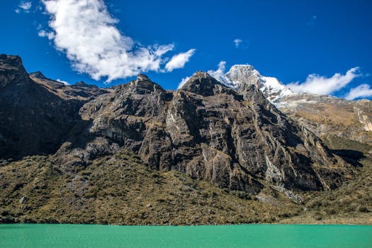 Breathtaking view of rocky mountain range above a serene turquoise lake on a clear day.