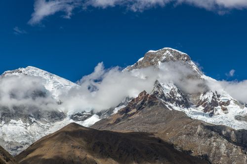 Free Breathtaking view of snowcapped mountains with clouds below against a clear blue sky. Stock Photo