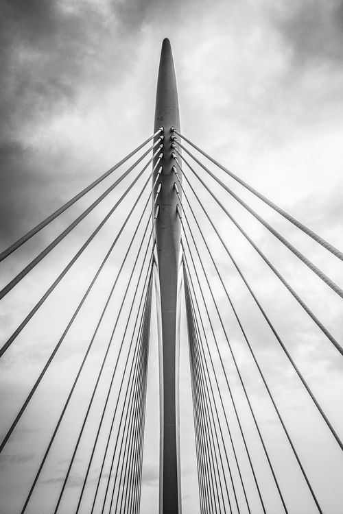 Free A striking black and white photo of a modern suspension bridge with metal cables and a dramatic sky. Stock Photo
