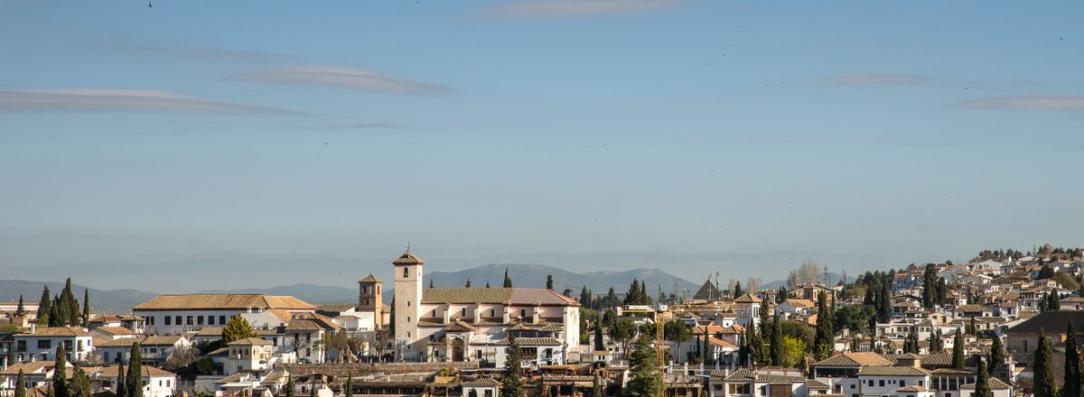 Panoramic view of a historic town with a prominent church tower under clear blue skies.