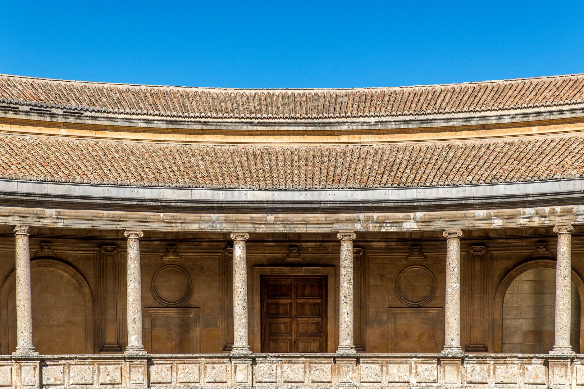 A classic architectural facade featuring circular design and stone columns under a clear blue sky.