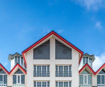 Symmetrical facade of a modern house with red roofs against a blue sky.