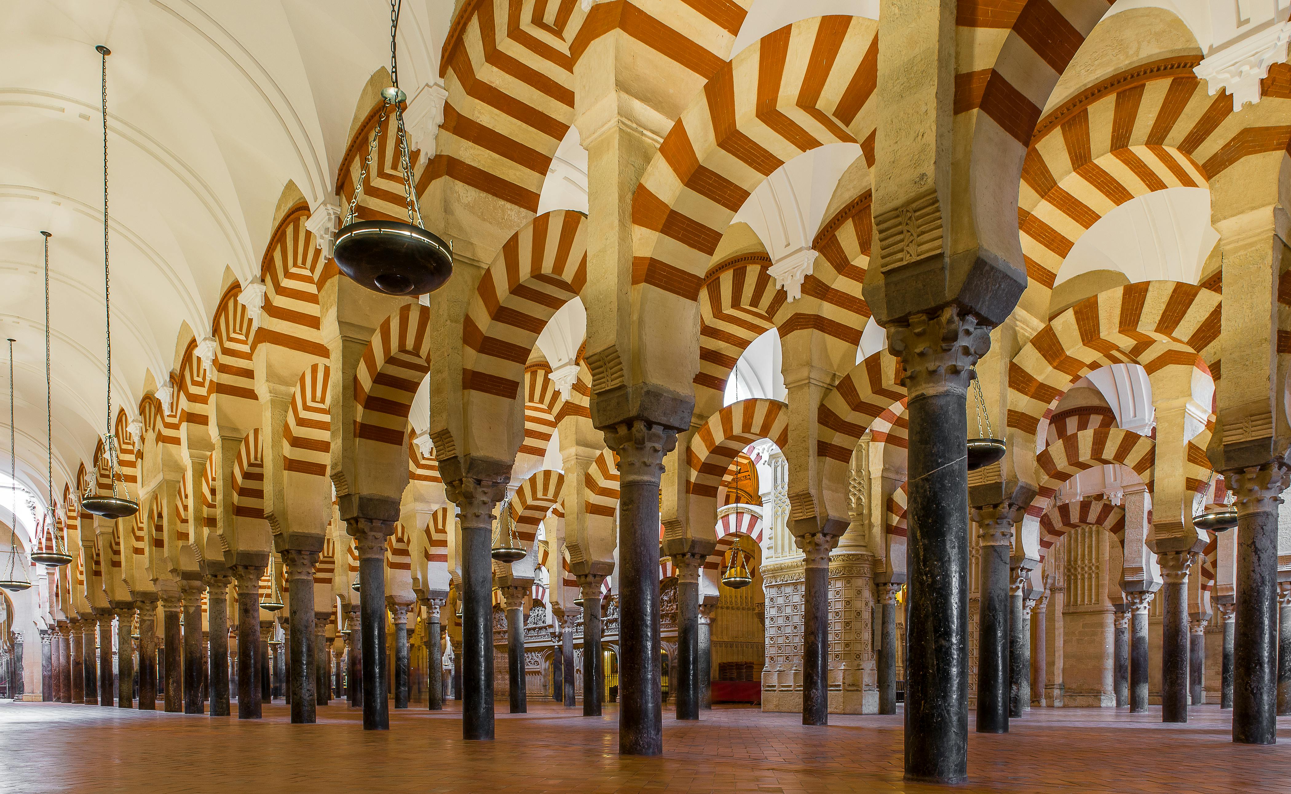 Great Mosque Of Cordoba Architecture With Red And White Striped Arches, Intricate Gold Mosaics, And Carved Marble Panels