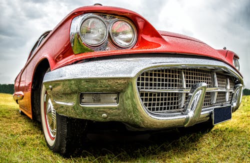 A Red Coupe Vintage Car Parked on the Grassy Field