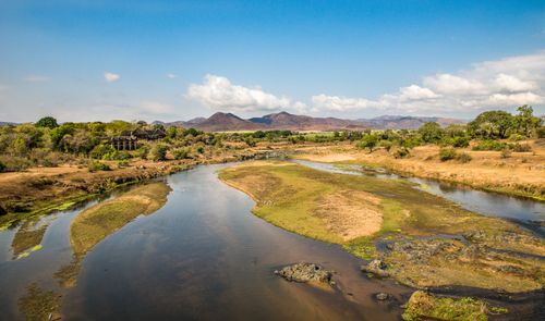 Free Serene river landscape with distant mountains and blue sky in the background. Stock Photo