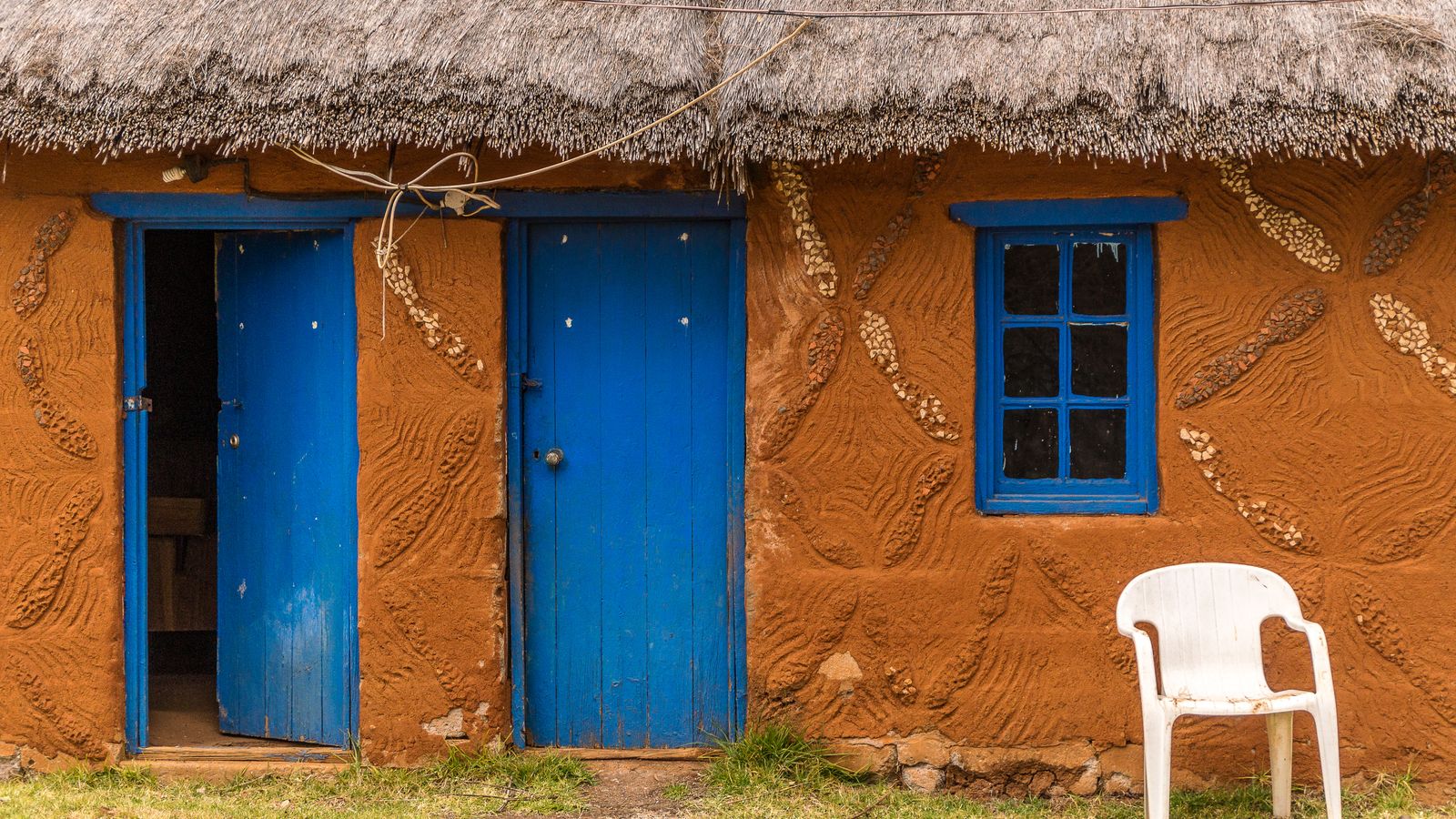 White plastic chair in front of old hut, Lesotho
