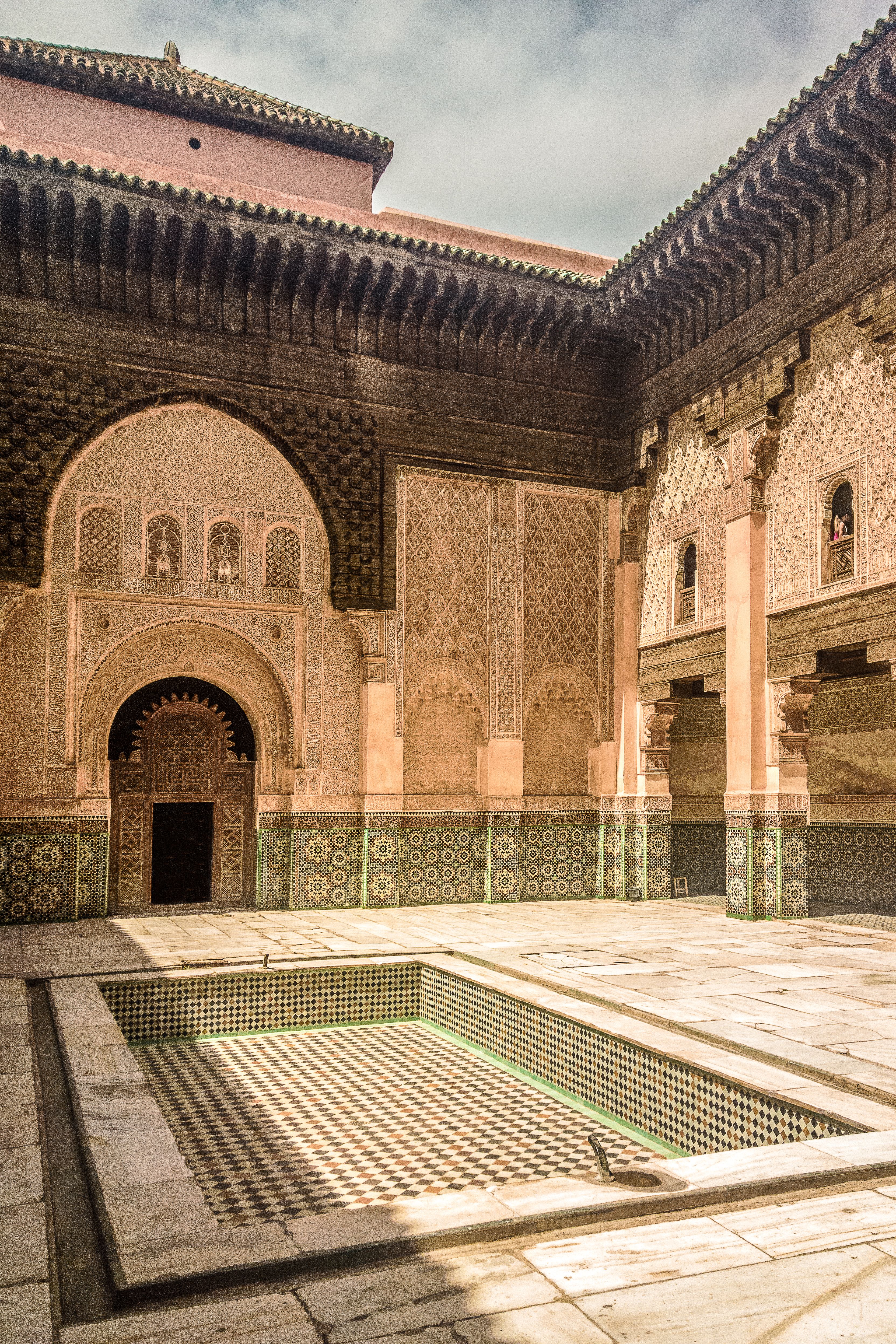 An empty Moorish courtyard showcasing intricate arches and patterned tiles under daylight.