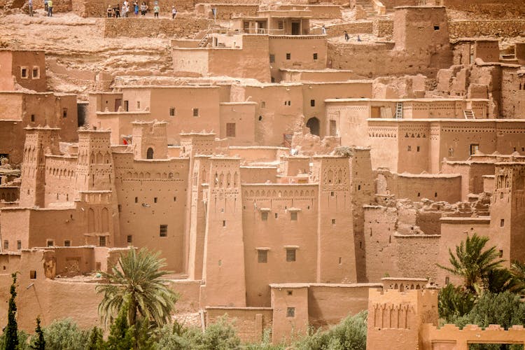 Group Of Tourists In Remains Of Ancient Town In Desert Oasis