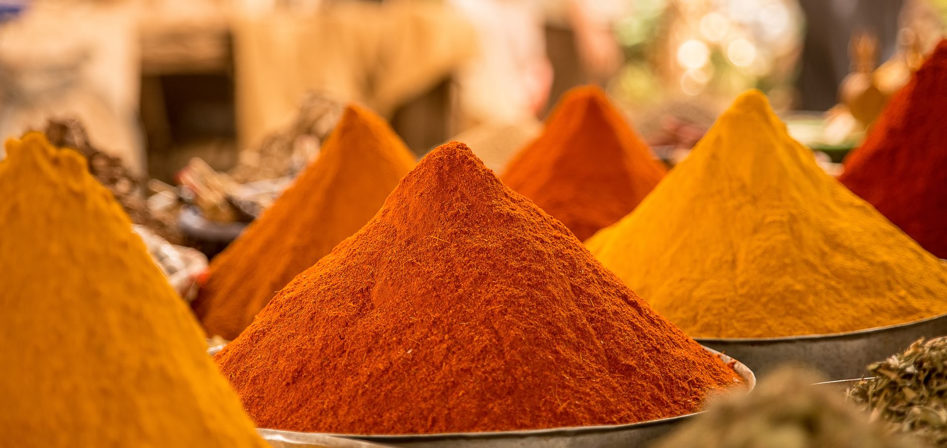 A close-up view of colorful powdered spices on display at a market stall.