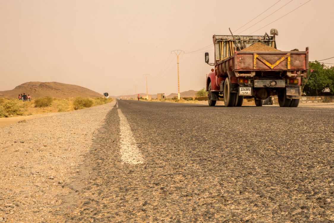 Pickup truck driving along a long, dusty desert road
