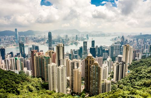 Free Stunning aerial view of Hong Kong's modern skyline and harbor under a cloudy sky. Stock Photo