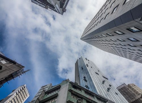 Free Dramatic perspective of city skyscrapers reaching towards a cloudy blue sky. Stock Photo