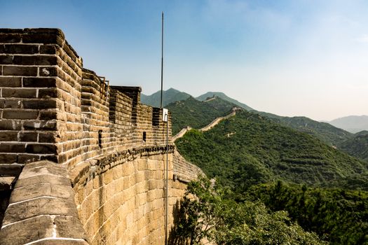 Stunning view of the Great Wall winding through lush hills under a clear sky.