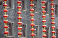 在传统建筑的背景下，悬挂着一排红色的中国灯笼，象征着节日