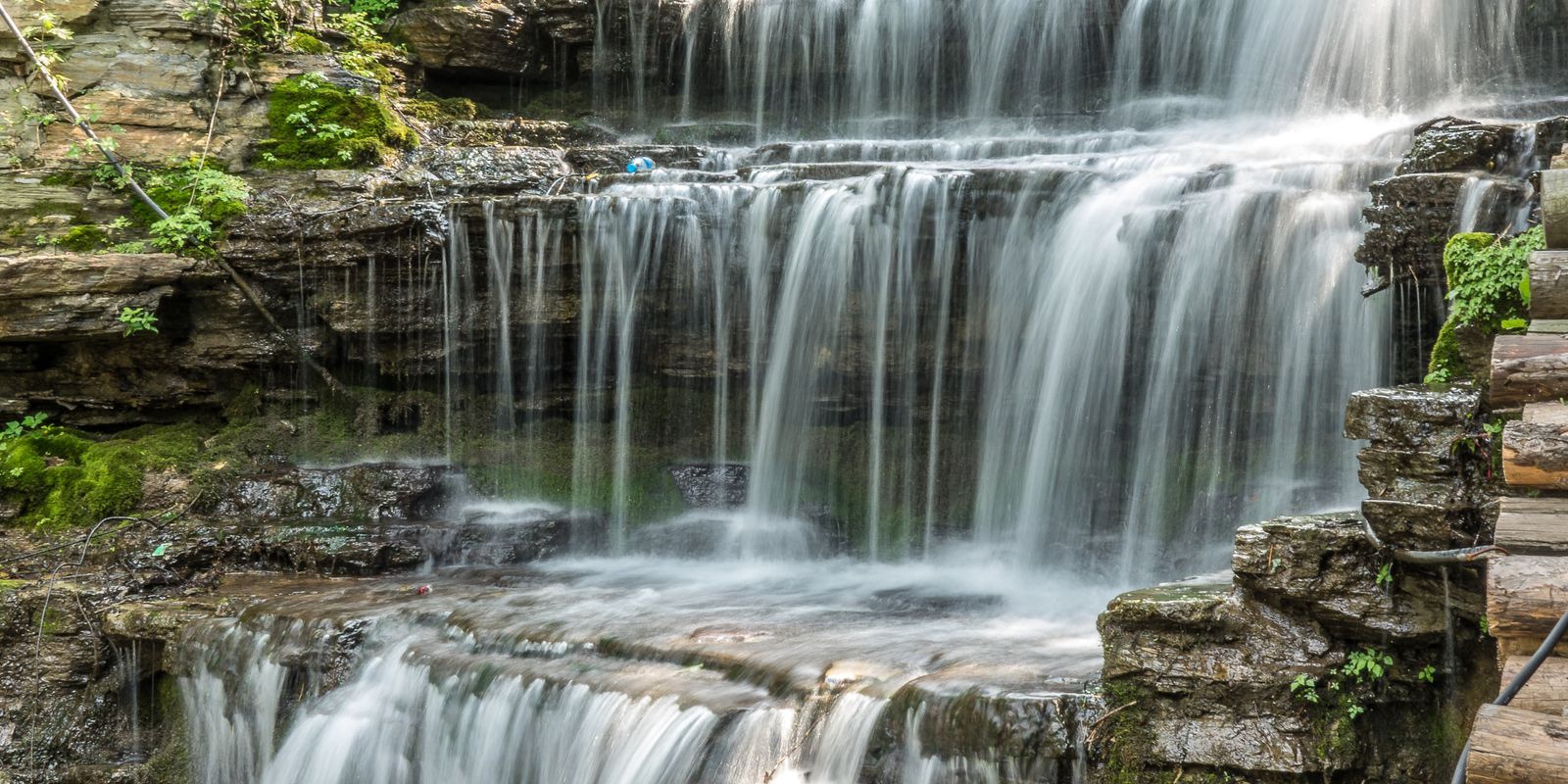 A cascading waterfall surrounded by lush green forest and rocks