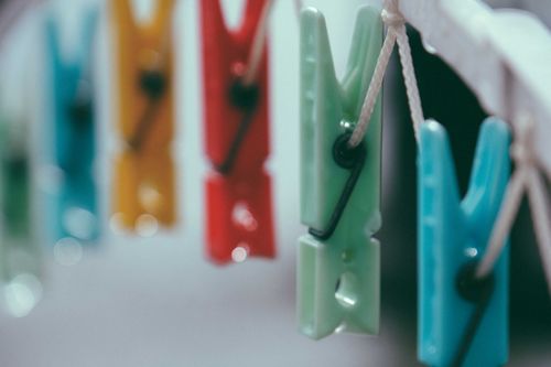 Free Closeup of small vibrant multi colored clothespins on white thin clothesline in daylight on blurred background Stock Photo