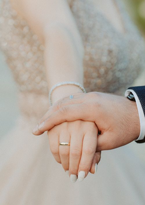Free Romantic close-up shot of a couple holding hands, displaying wedding rings, symbolizing love and unity. Stock Photo