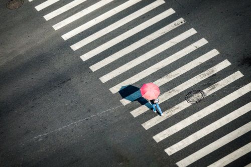 Free Top view of person with red umbrella crossing a zebra crosswalk. Stock Photo