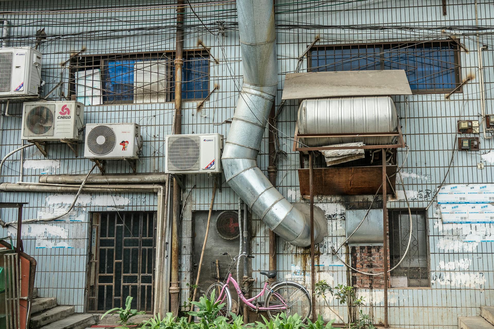 An urban building facade featuring multiple air conditioning units and ductwork.