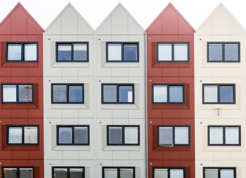 Front view of modern apartment building facade with contrasting colors and geometric windows.