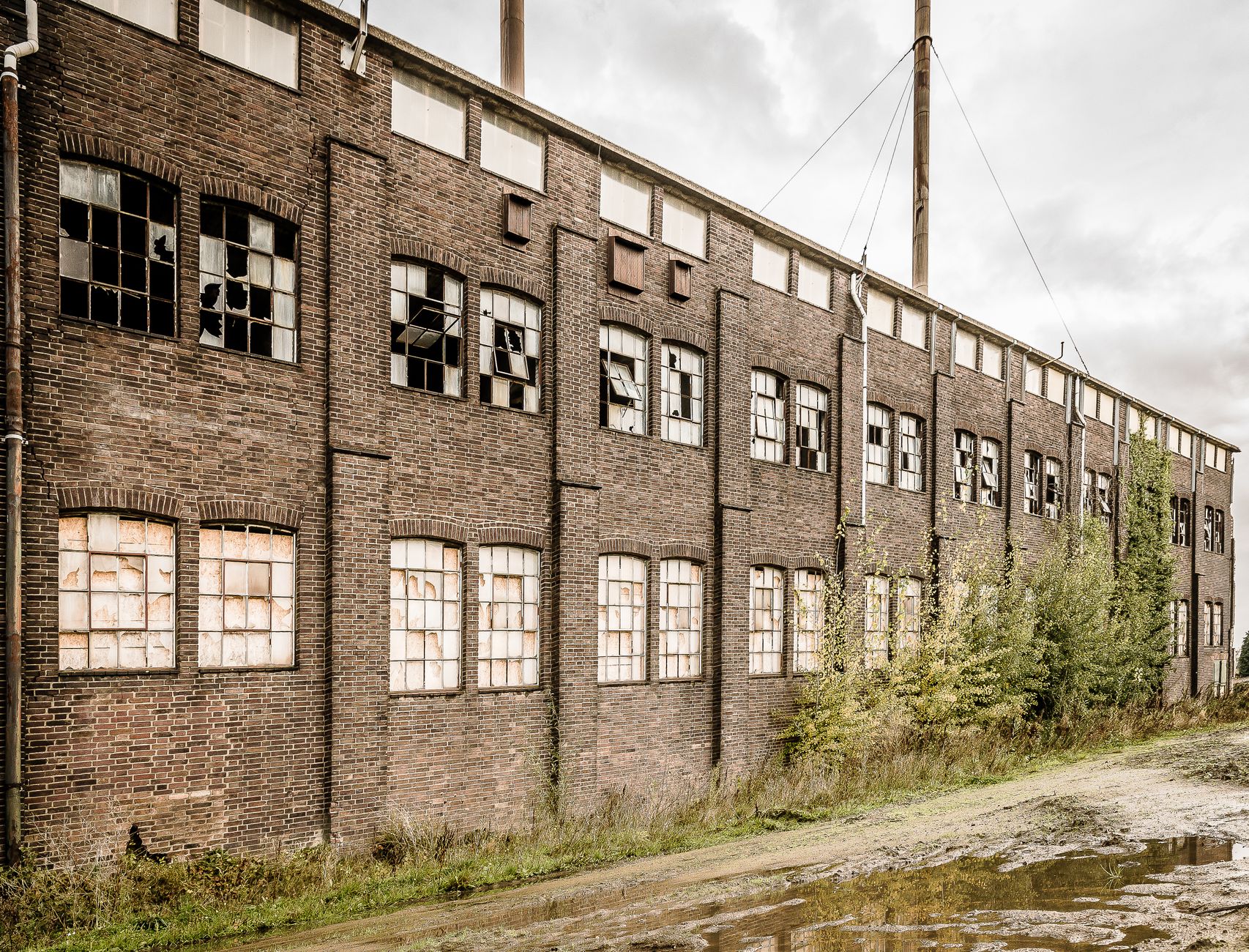 Exterior of an old, abandoned industrial building with broken windows and weathered facade.
