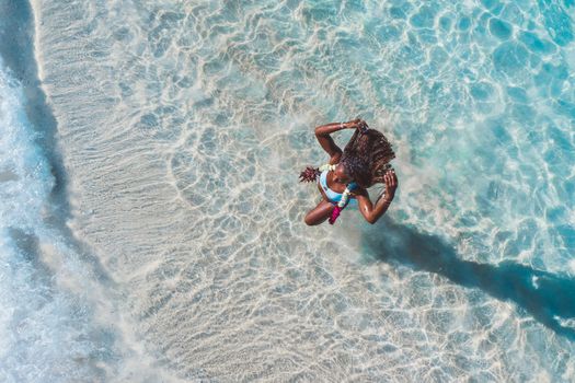 Aerial view of a woman swimming in clear blue ocean waters, capturing a carefree summer vibe.