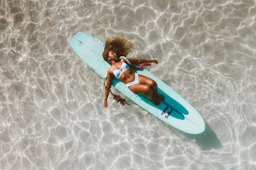 Overhead Shot of a Woman in a Bikini Lying on a Surfboard