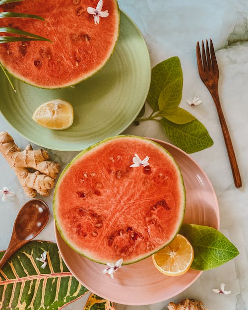 Photo of a Halved Watermelon Near a Wooden Spoon