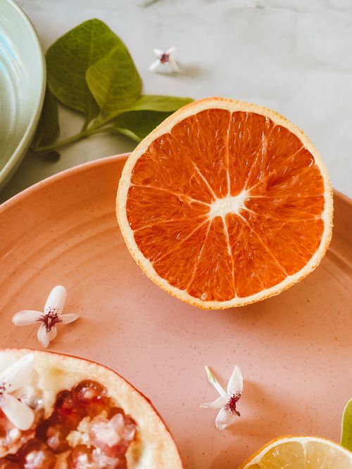 Free Close-up of halved grapefruit with delicate blossoms on a peach plate. Stock Photo
