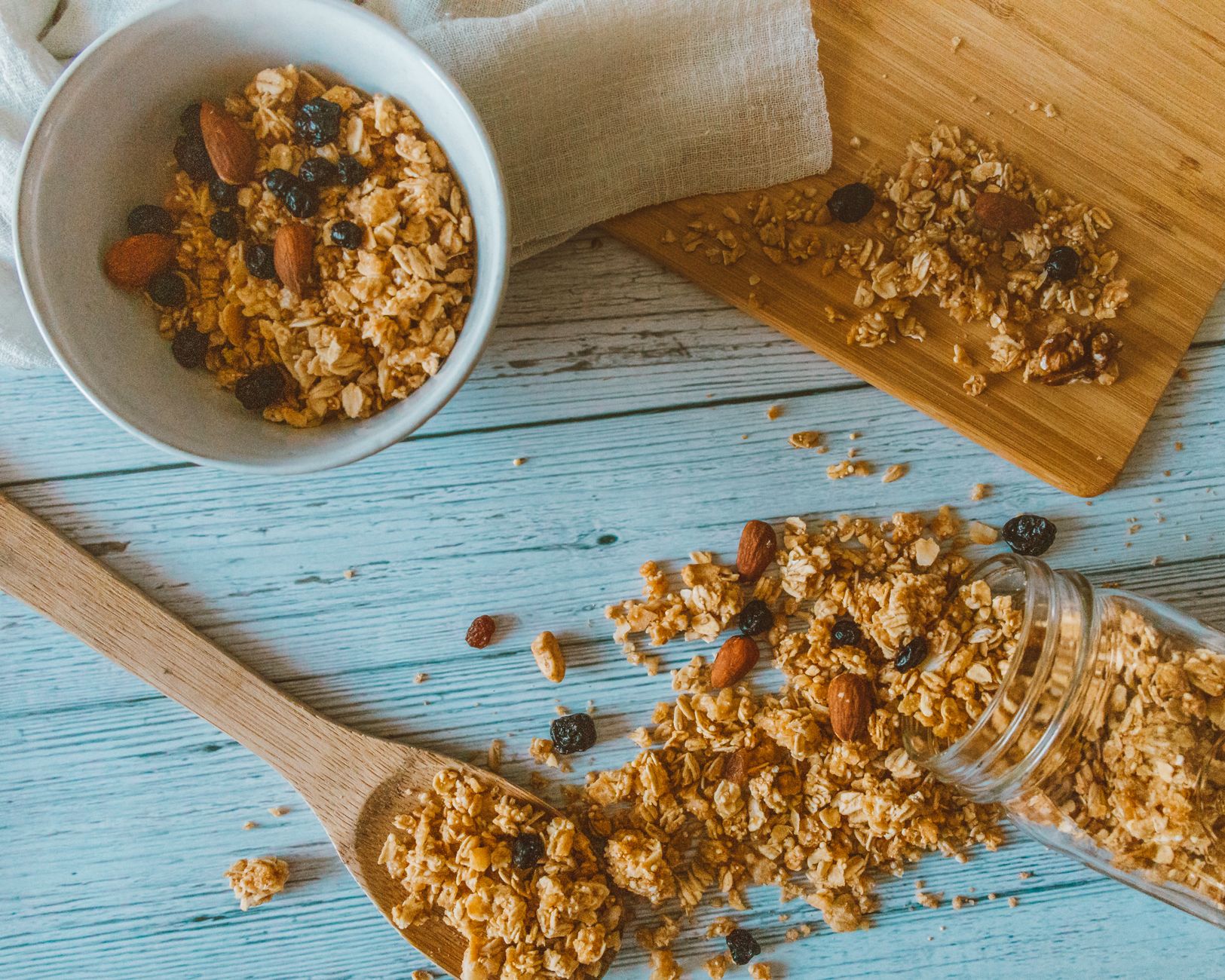 Delicious Grain-Free Granola: A Crunchy Breakfast Delight Top view of granola with almonds and berries spilled from a jar onto a wooden table.