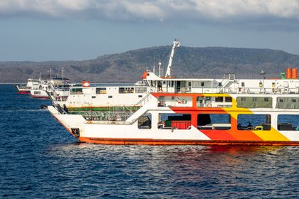 Ferries docked in a harbour below mountains. Photo by Mike van Schoonderwalt on Pexels