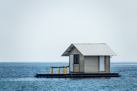 A solitary hut floats on a calm sea, perfect for vacation or escape.