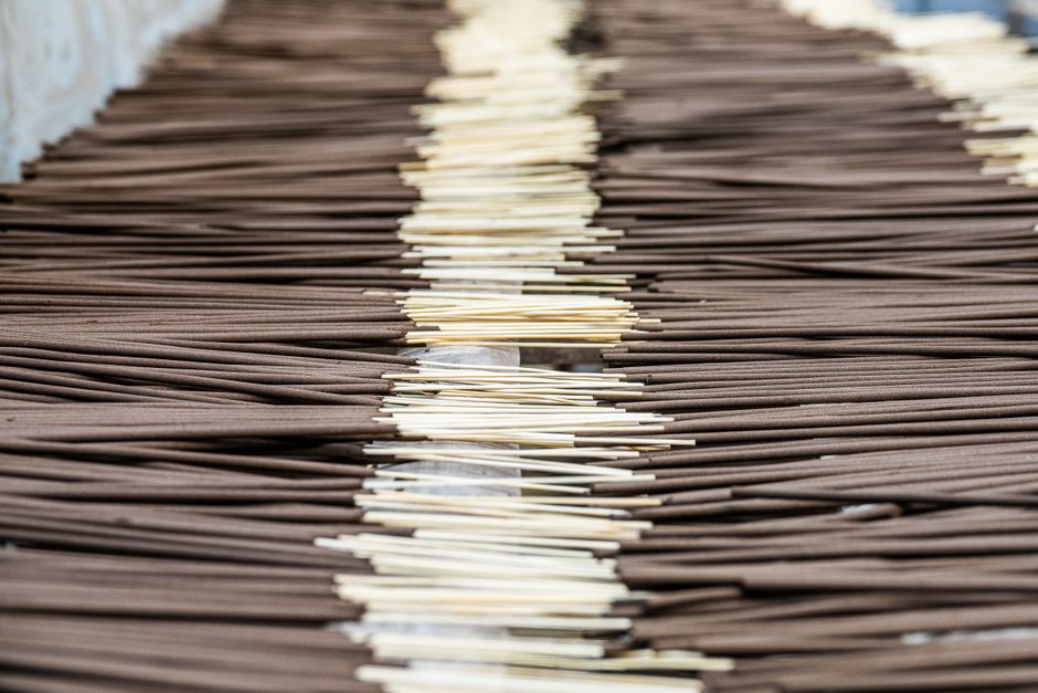 A close-up view of incense sticks aligned in a manufacturing setting, showcasing their distinct arrangement.
