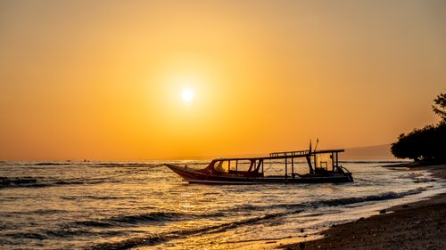 Free A captivating sunset over the sea with a silhouette of a boat gently floating on calm waters. Stock Photo