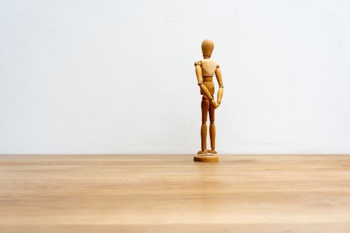 Free A Wooden Human Figure on Brown Surface Stock Photo