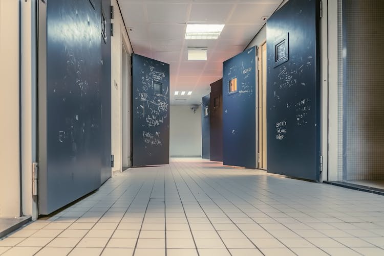 Low Angle Shot Of Open Doors Along The Tiled Hallway