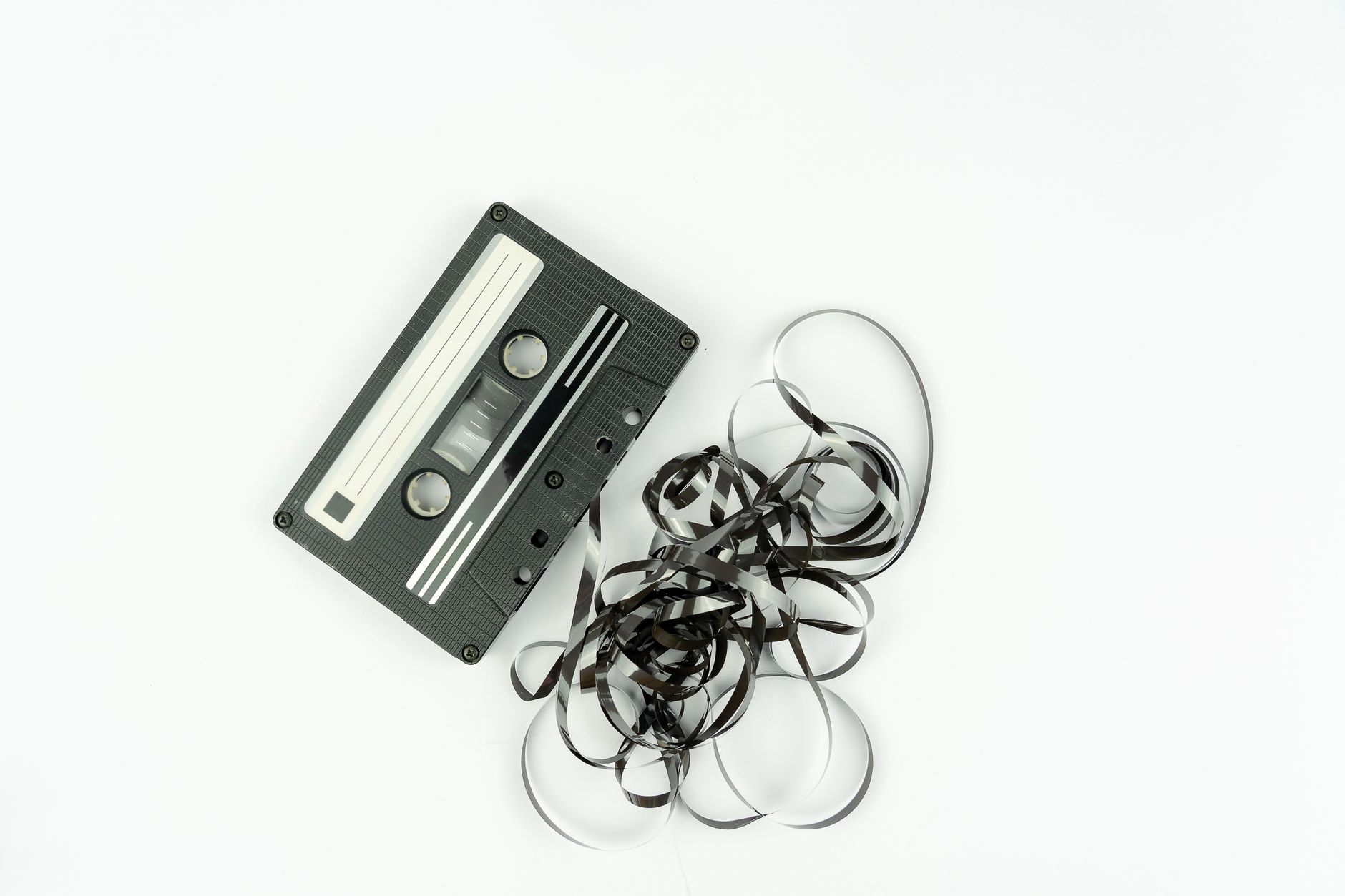 A vintage cassette tape with tangled tape on a white background, evoking nostalgia.