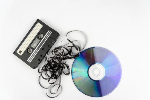 A nostalgic look at a cassette tape and CD on a white backdrop, showcasing vintage technology.