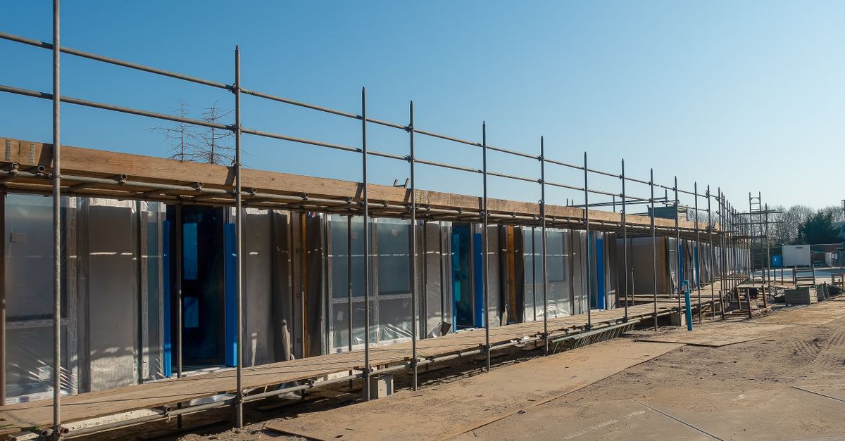 A clear day view of a construction site with scaffolding around an unfinished building.