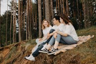 一群朋友在宁静的森林里铺开毯子野餐，他们分享着微笑，愉快地交谈