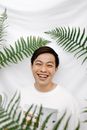 一个快乐的人脸上带着喜悦的表情，站在绿色的蕨类植物叶子之间