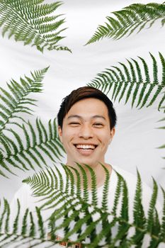 一个开朗的男人在生机勃勃的绿色蕨类植物中微笑，展现着欢乐与自然之美