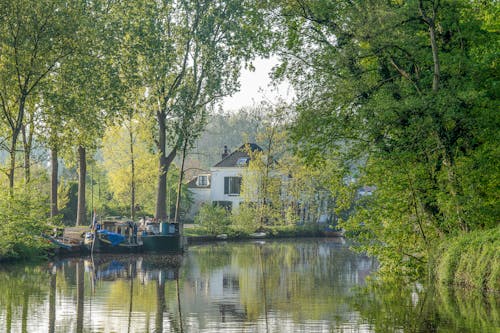 Free  Boats and House on River Near Green Trees Stock Photo