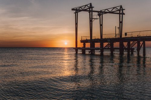 Free Capture the serene beauty of a sunset over a rusty pier by the sea. Stock Photo