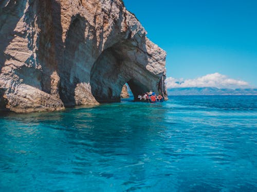 People Riding on Boat Near the Rock Formation Under the Blue Sky