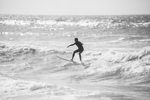 A Grayscale Photo of a Person Surfing on the Sea