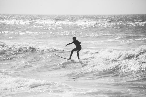 Free Silhouette of a surfer riding waves in Ericeira, Portugal, in stunning black and white. Stock Photo