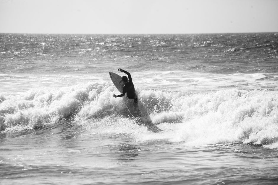 Black and white photograph of a surfer riding waves at Ericeira, Portugal.
