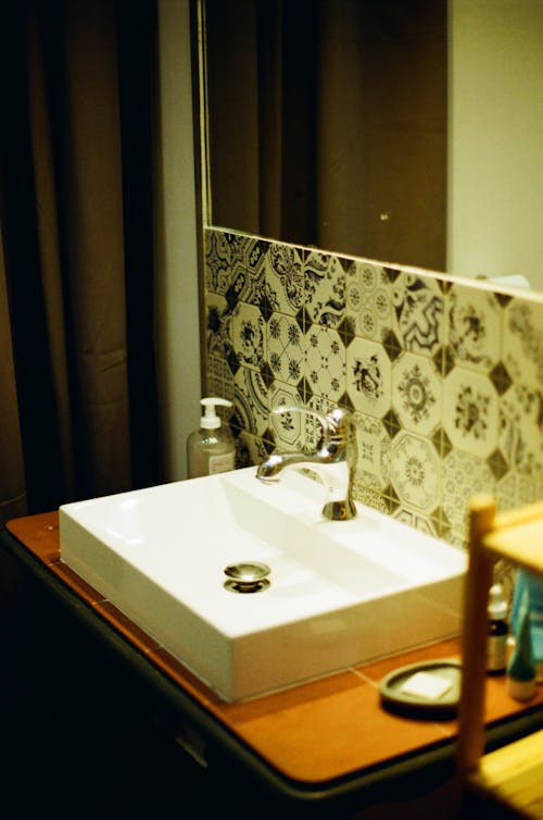 Painted Ceramic Tiles under Mirror by Sink in Bathroom