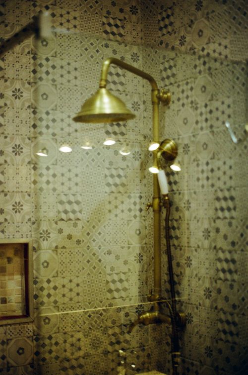 Free Vintage brass showerhead against patterned tile in an elegant bathroom setting, Nice, France. Stock Photo
